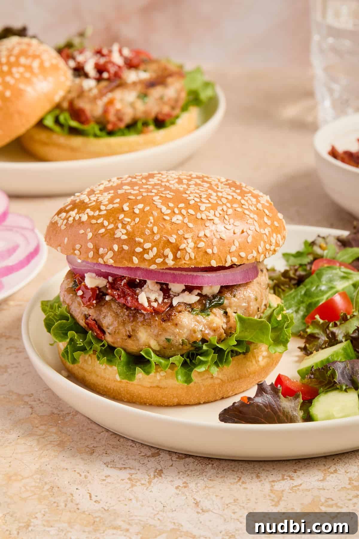 Spinach and Feta Turkey Burgers with Garlic Yogurt Sauce 2 Spinach and feta turkey burger on hamburger bun with lettuce, onion, feta crumbles and sun-dried tomatoes.