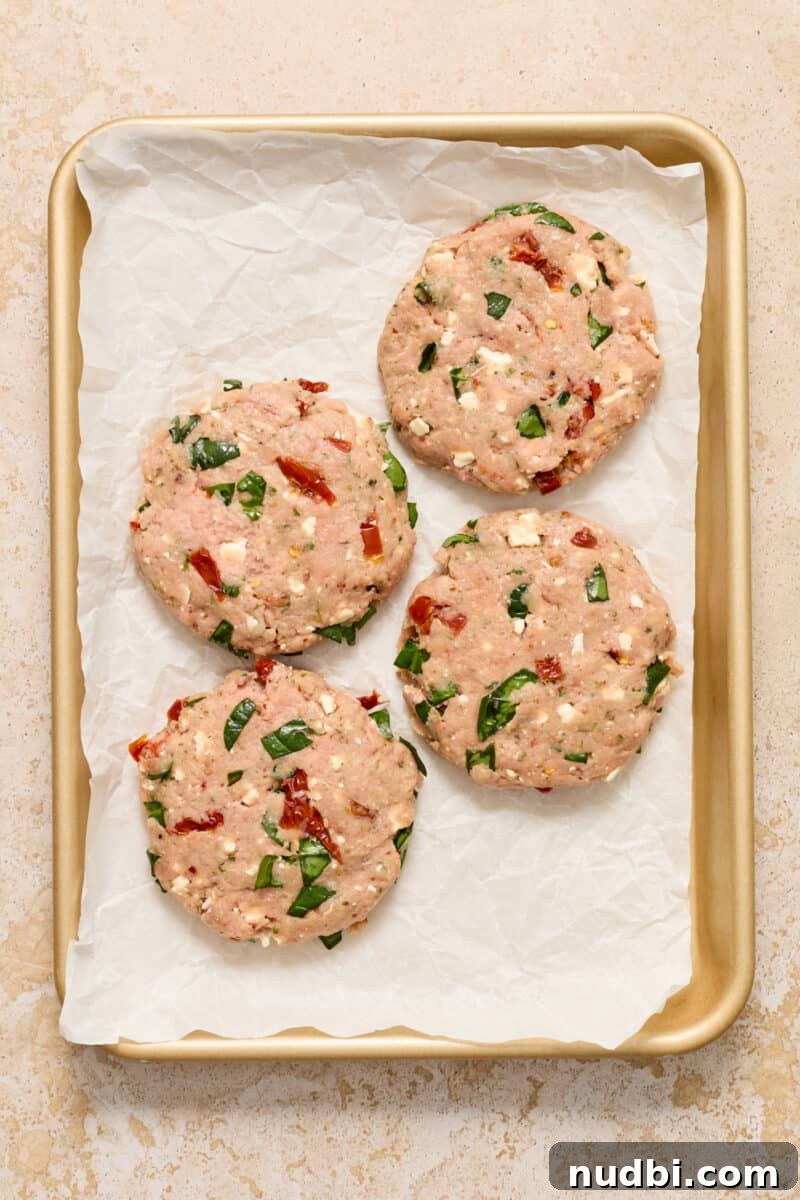 Spinach and Feta Turkey Burgers with Garlic Yogurt Sauce 6 Ground turkey burger patties on parchment lined baking sheet.