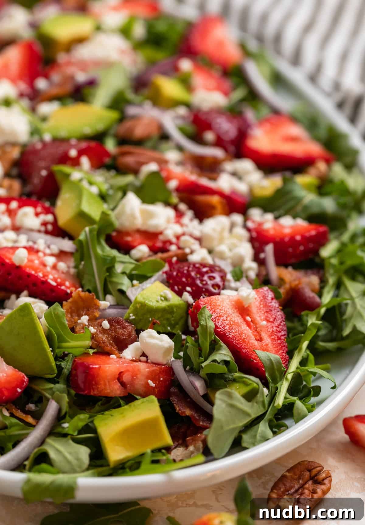 Strawberry and Goat Cheese Salad with Balsamic Glaze Recipe 2 Strawberry goat cheese salad on white plate with avocado, arugula, bacon and pecans.