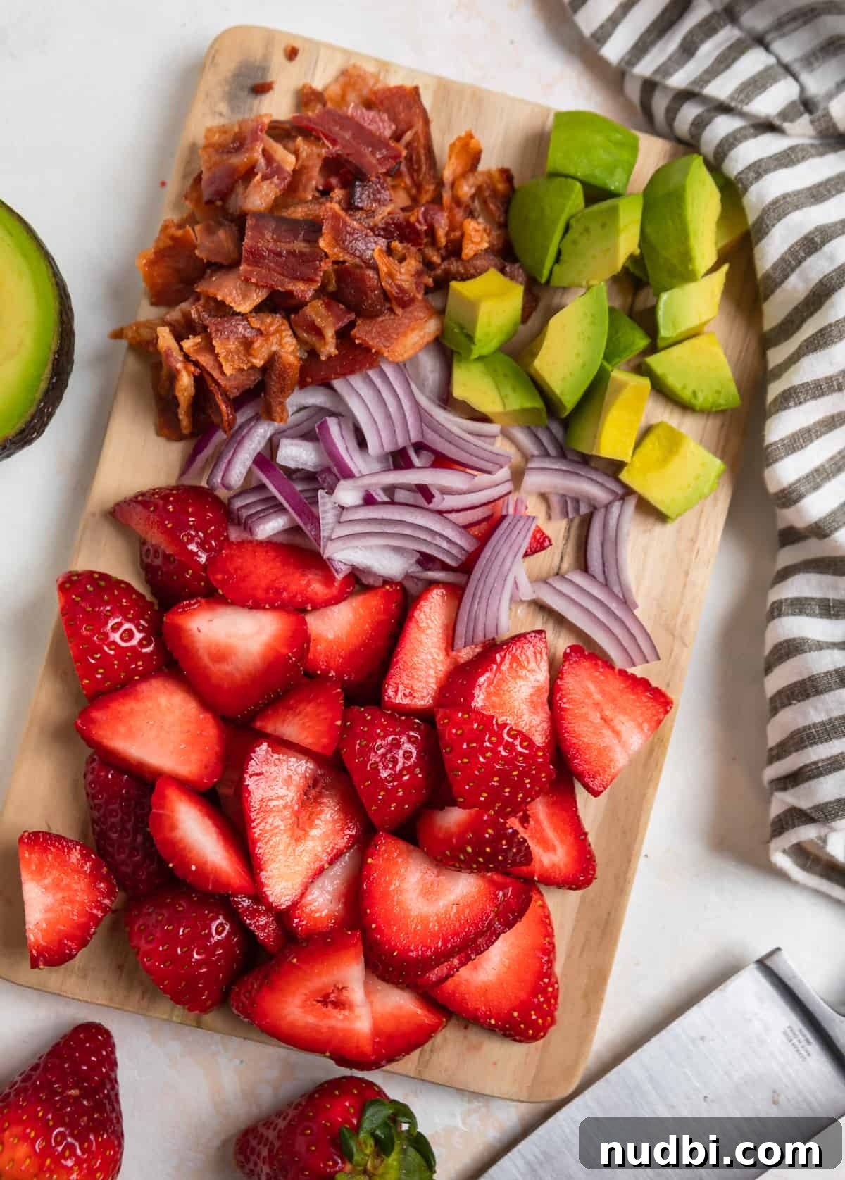 Strawberry and Goat Cheese Salad with Balsamic Glaze Recipe 4 Cutting board with sliced strawberries, avocado, red onion, and bacon.