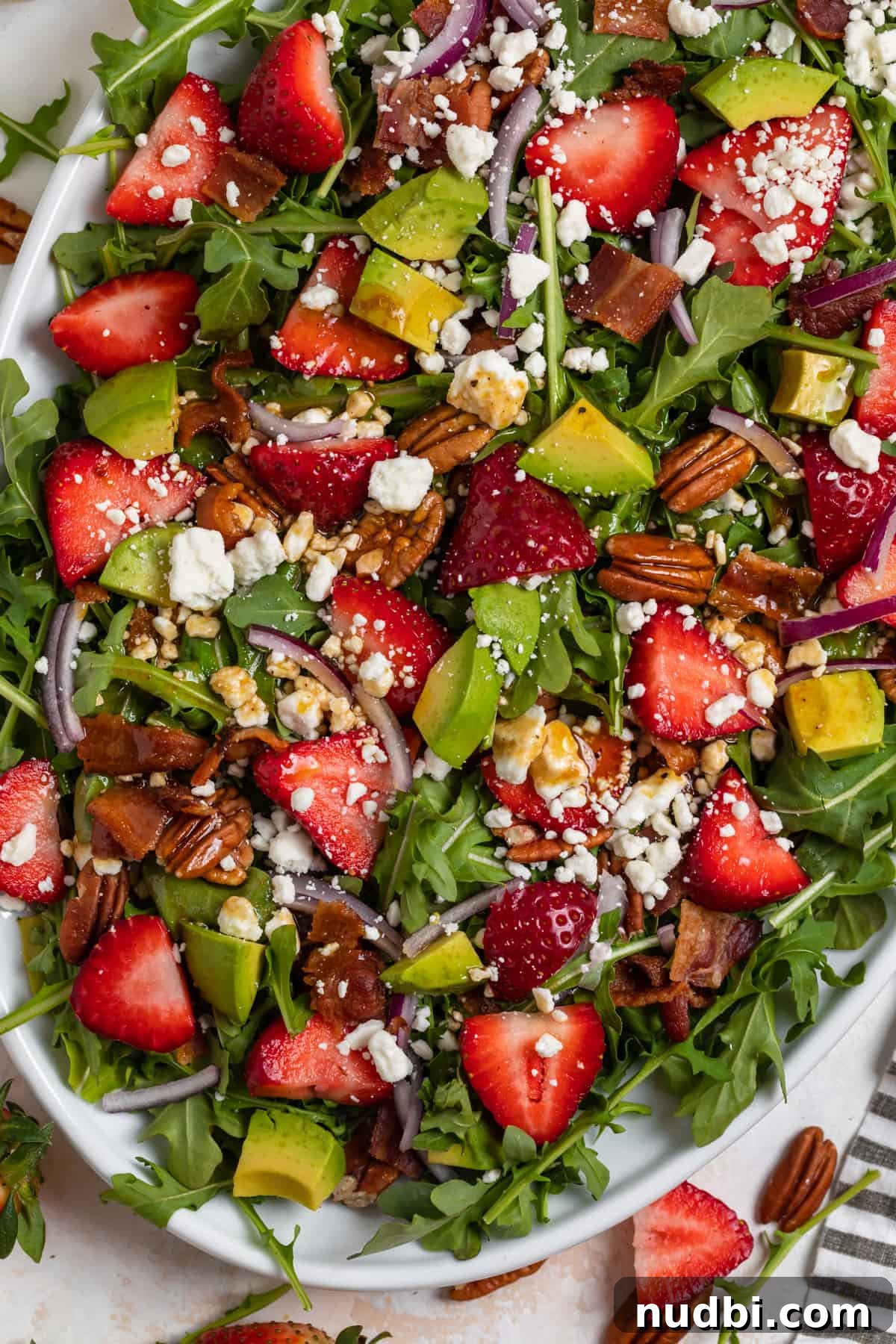 Strawberry and Goat Cheese Salad with Balsamic Glaze Recipe 5 Strawberry goat cheese and arugula salad on white dish with lined linen laying beside it.