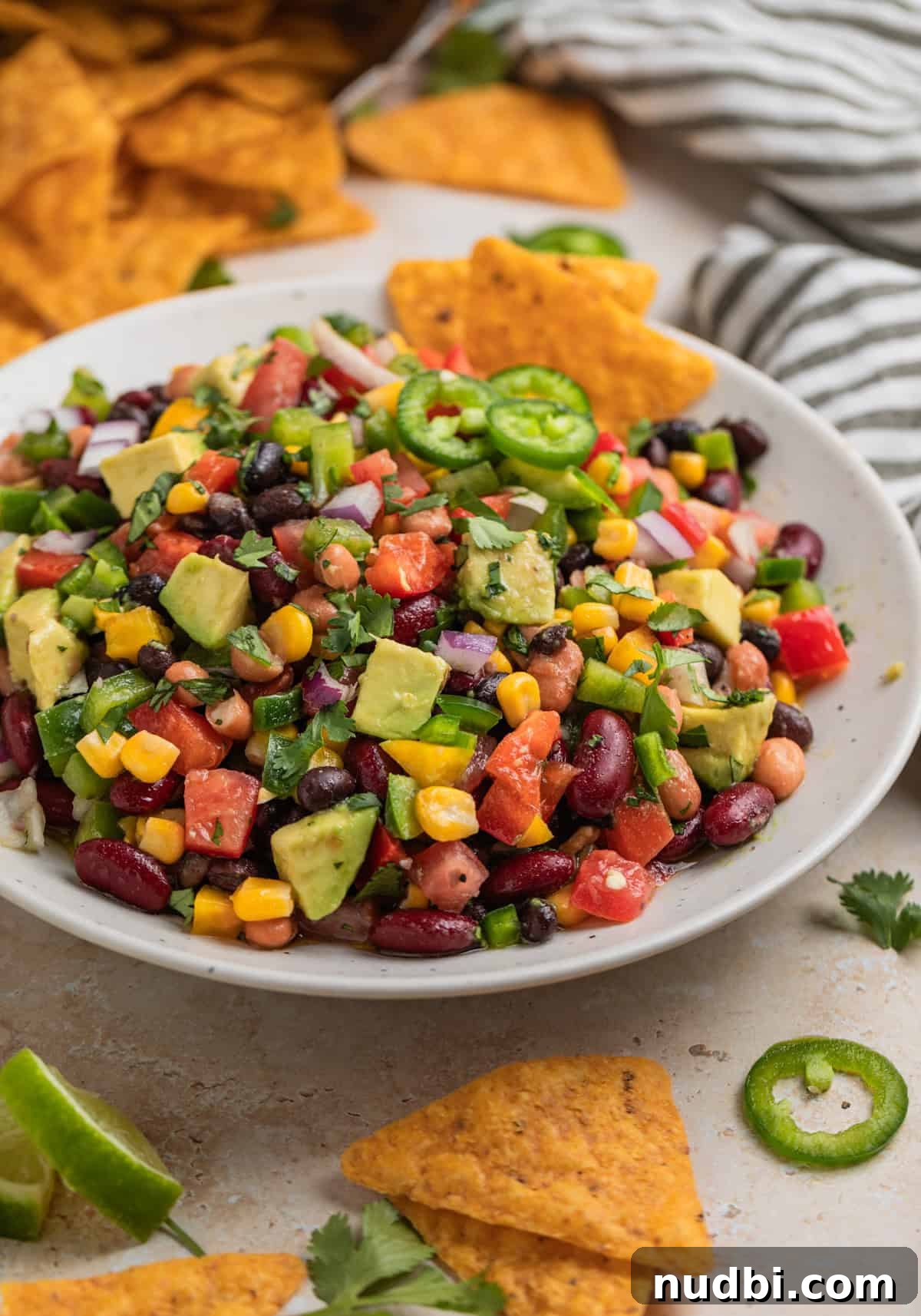 Southwestern Three-Bean, Corn & Avocado Salad Recipe 9 Chips dipped into bean and avocado salad with corn and topped with chopped cilantro.
