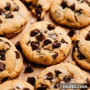 Small-Batch One-Bowl Chocolate Chip Cookies 11 Chocolate chip cookies lined on parchment paper with crumbs and chocolate chips surrounding.