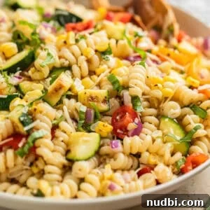 Grilled Zucchini Pasta Salad with Lemon Garlic Dressing 11 Zucchini pasta salad in serving bowl with wood spoon.