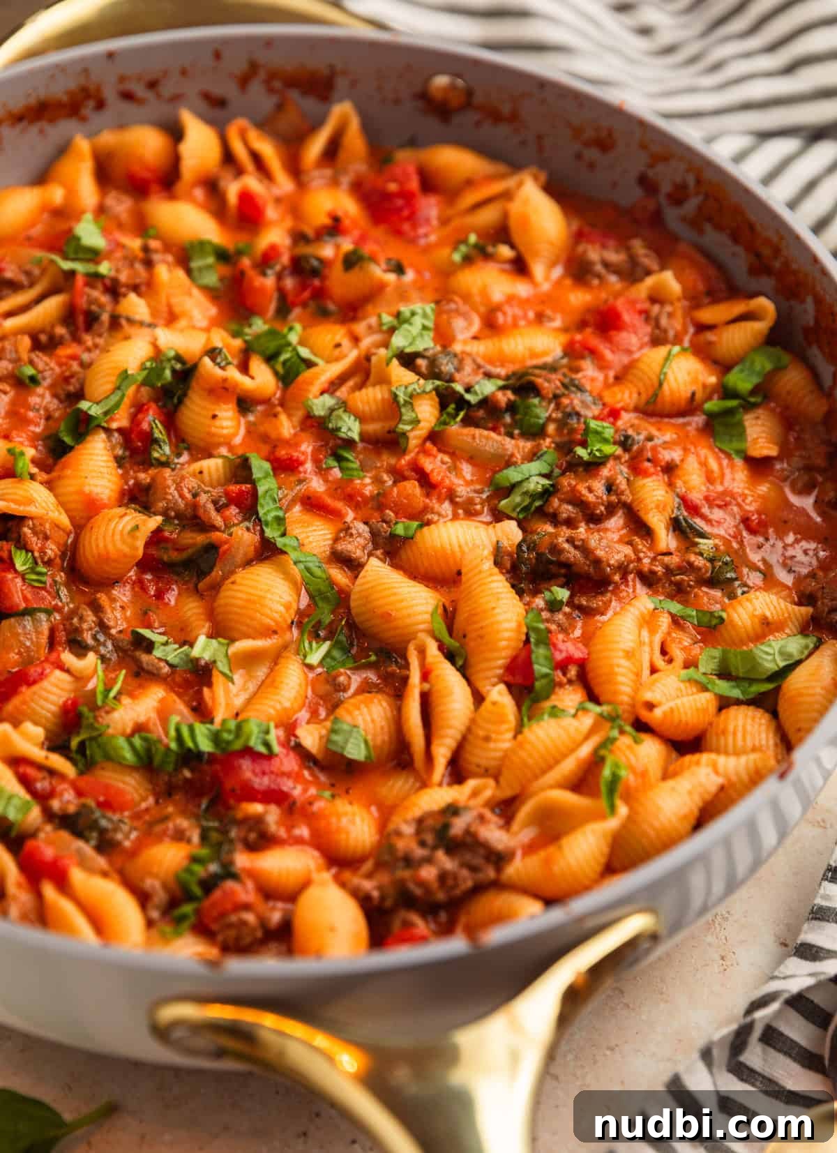 One-Skillet Ground Beef Pasta Skillet Meal 11 Beef and shells in pan with basil over top.
