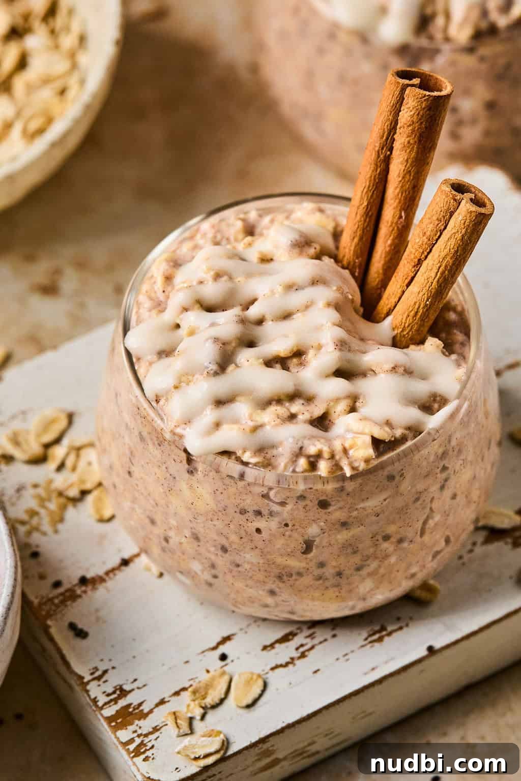 Cinnamon Roll Overnight Oats Recipe for Quick Morning Bliss 2 Cinnamon roll overnight oats in glass cup topped with a white icing drizzle.
