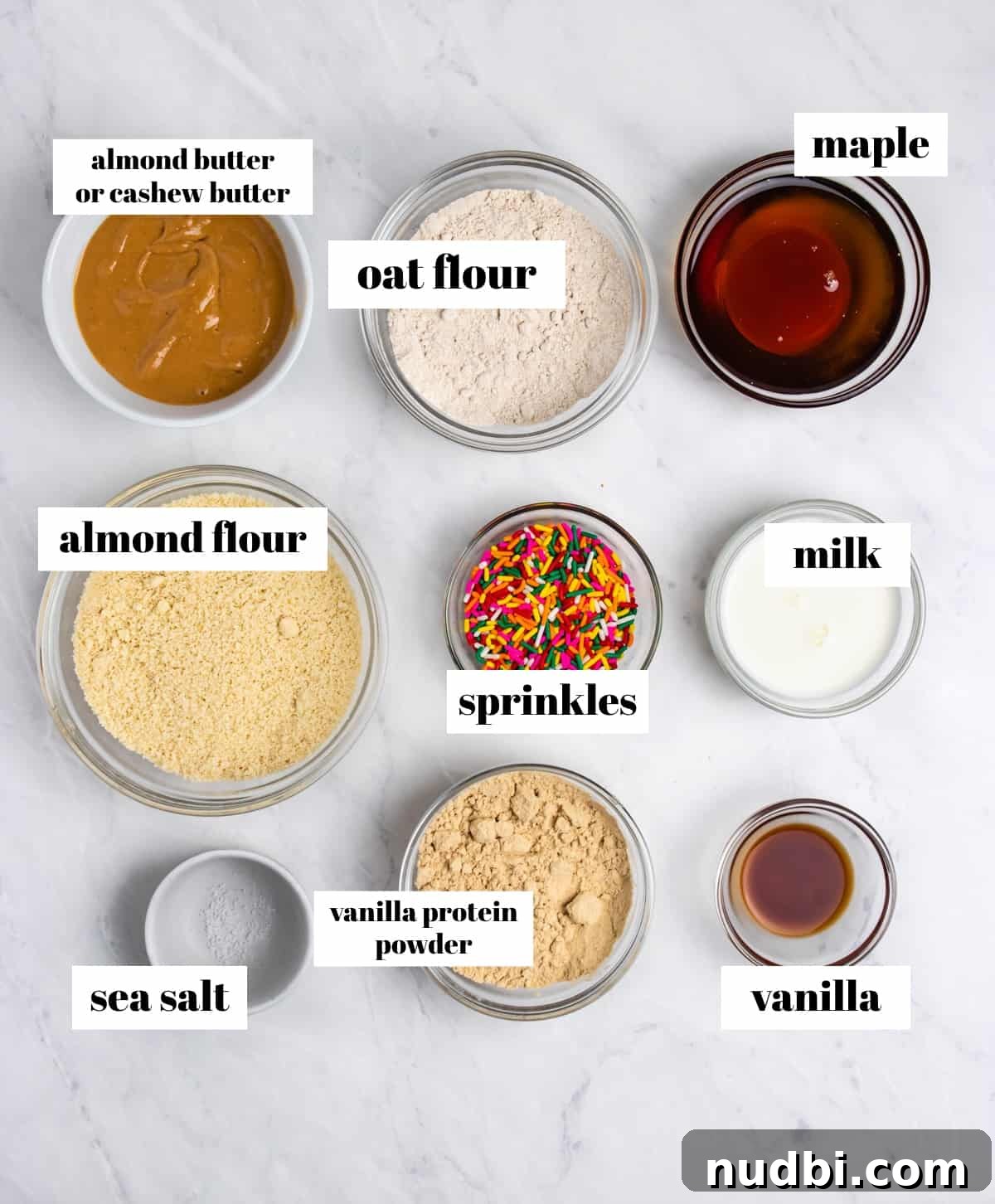 Birthday Cake Protein Bars Recipe — High-Protein Snack for Parties 3 Almond flour, protein powder, maple syrup, sprinkles and other ingredients labeled on counter.