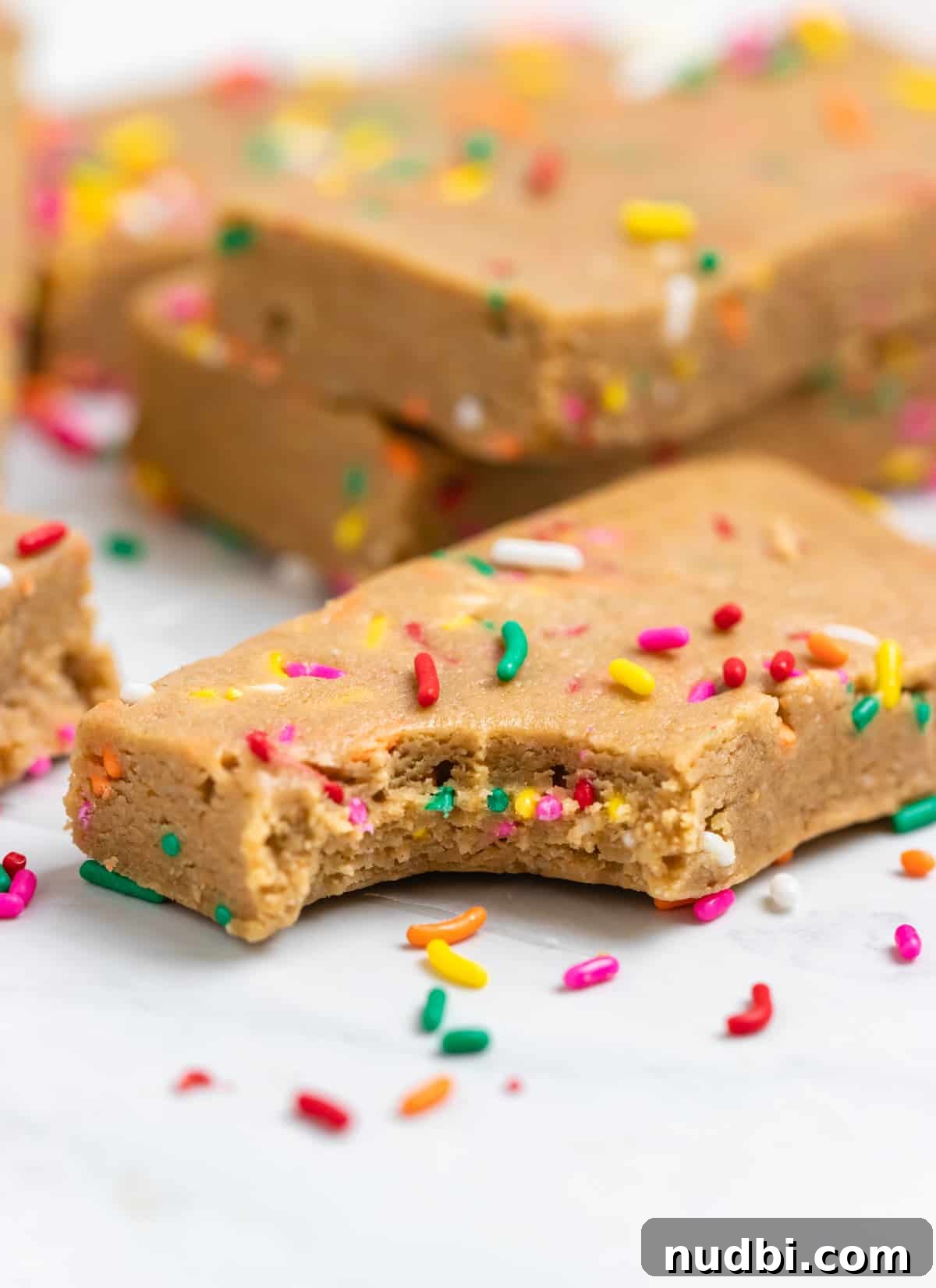 Birthday Cake Protein Bars Recipe — High-Protein Snack for Parties 7 Bite shot of protein bar on counter with rainbow sprinkles.