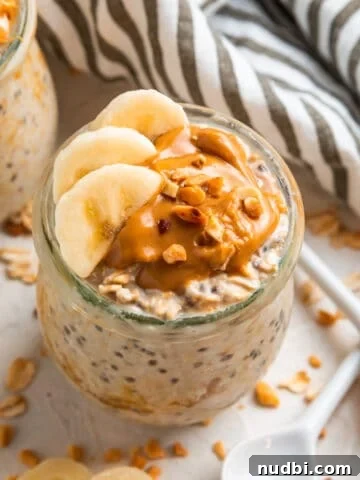 Glass jar with overnight oats topped with sliced banana and topped with peanut butter.