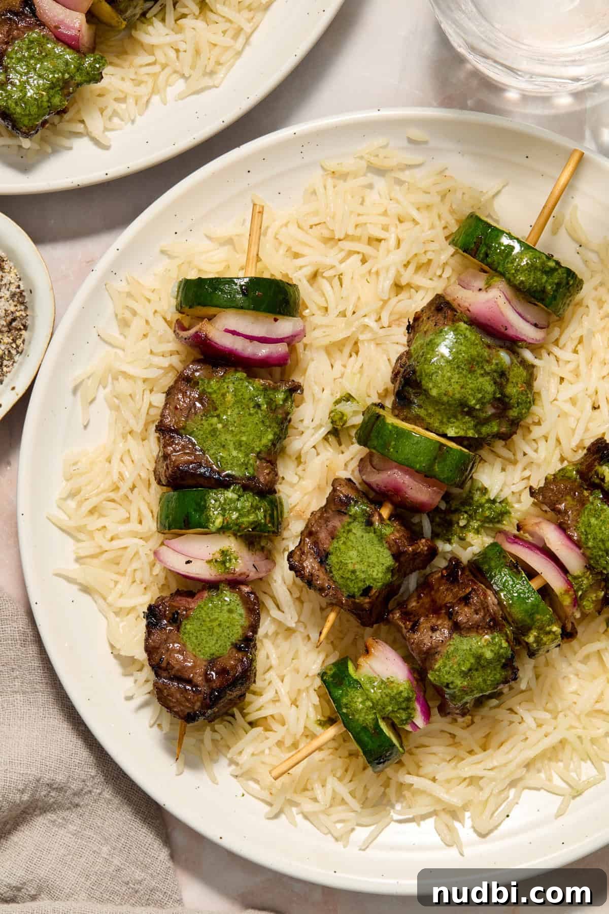 Grilled Steak Kabobs with Zesty Cilantro Chimichurri 2 Grilled steak kabobs with zucchini and onion over rice and topped with cilantro chimichurri.
