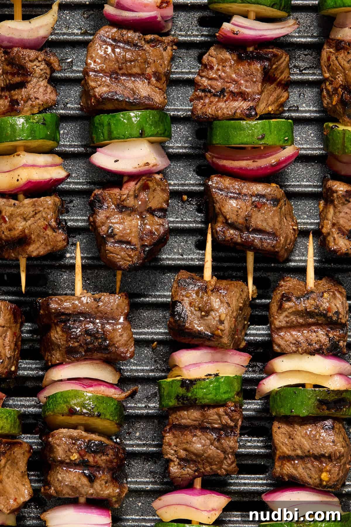 Grilled Steak Kabobs with Zesty Cilantro Chimichurri 3 Grilled steak kabobs arranged in rows on grill.
