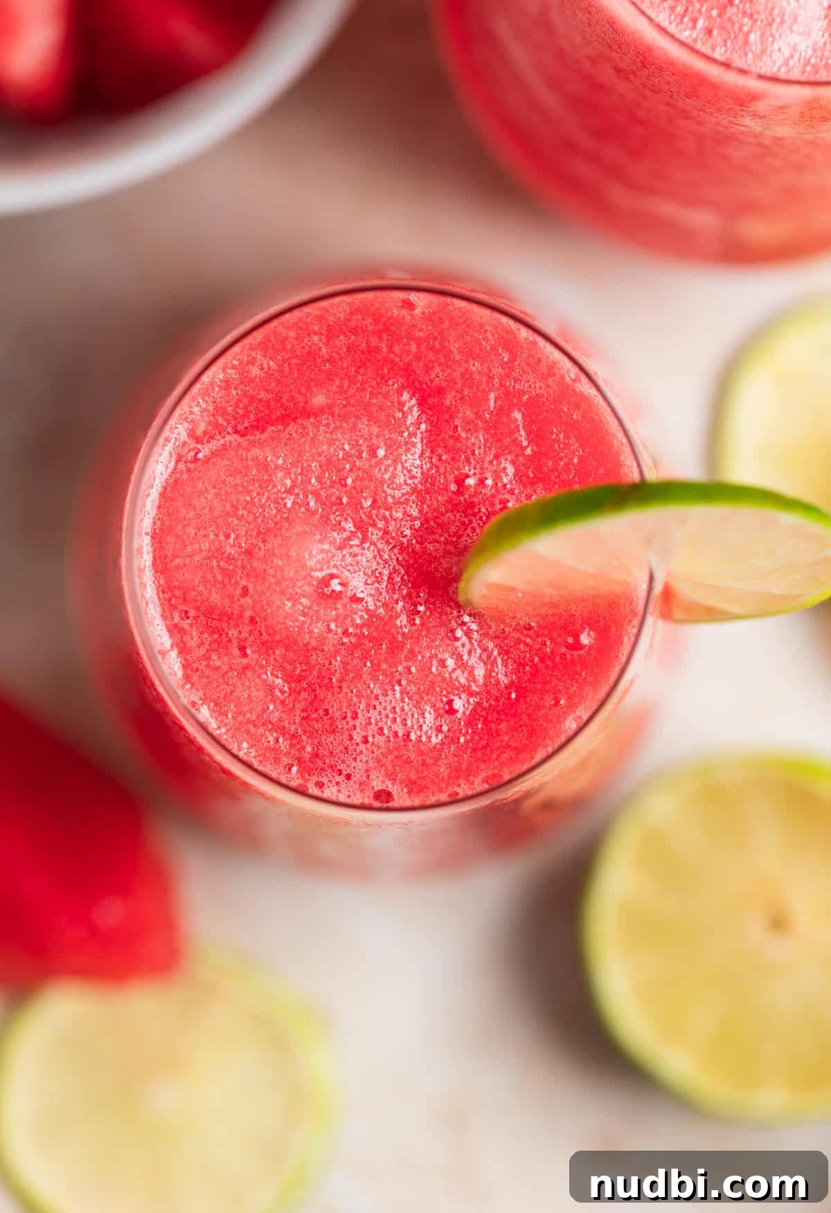 Watermelon Frosé Recipe: Frozen Rosé Cocktail for Summer 6 View inside wine glass with frozen watermelon rosé with a lime slice for garnish.