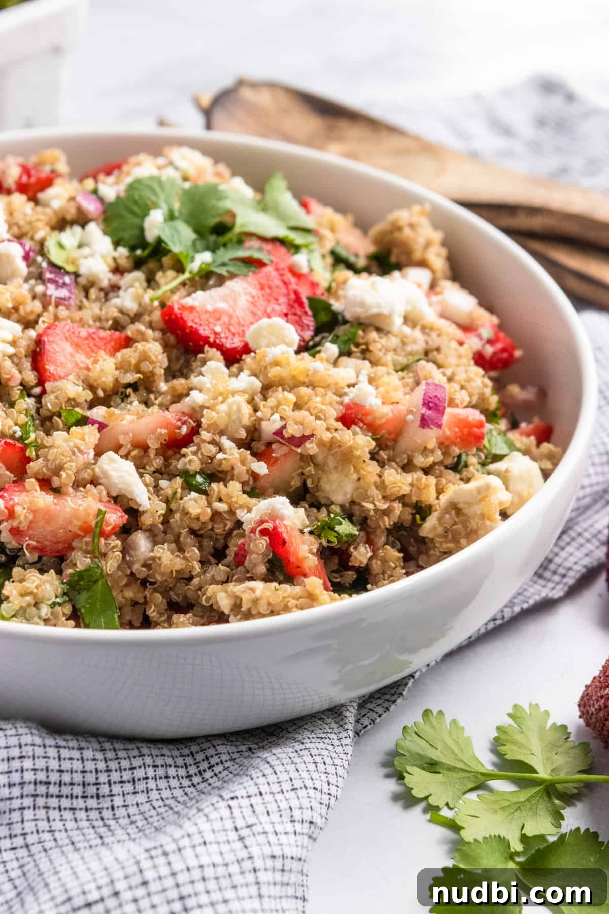 Summer Strawberry Quinoa Salad with Basil and Feta 2 Strawberry summer quinoa salad in white bowl with serving utensils.