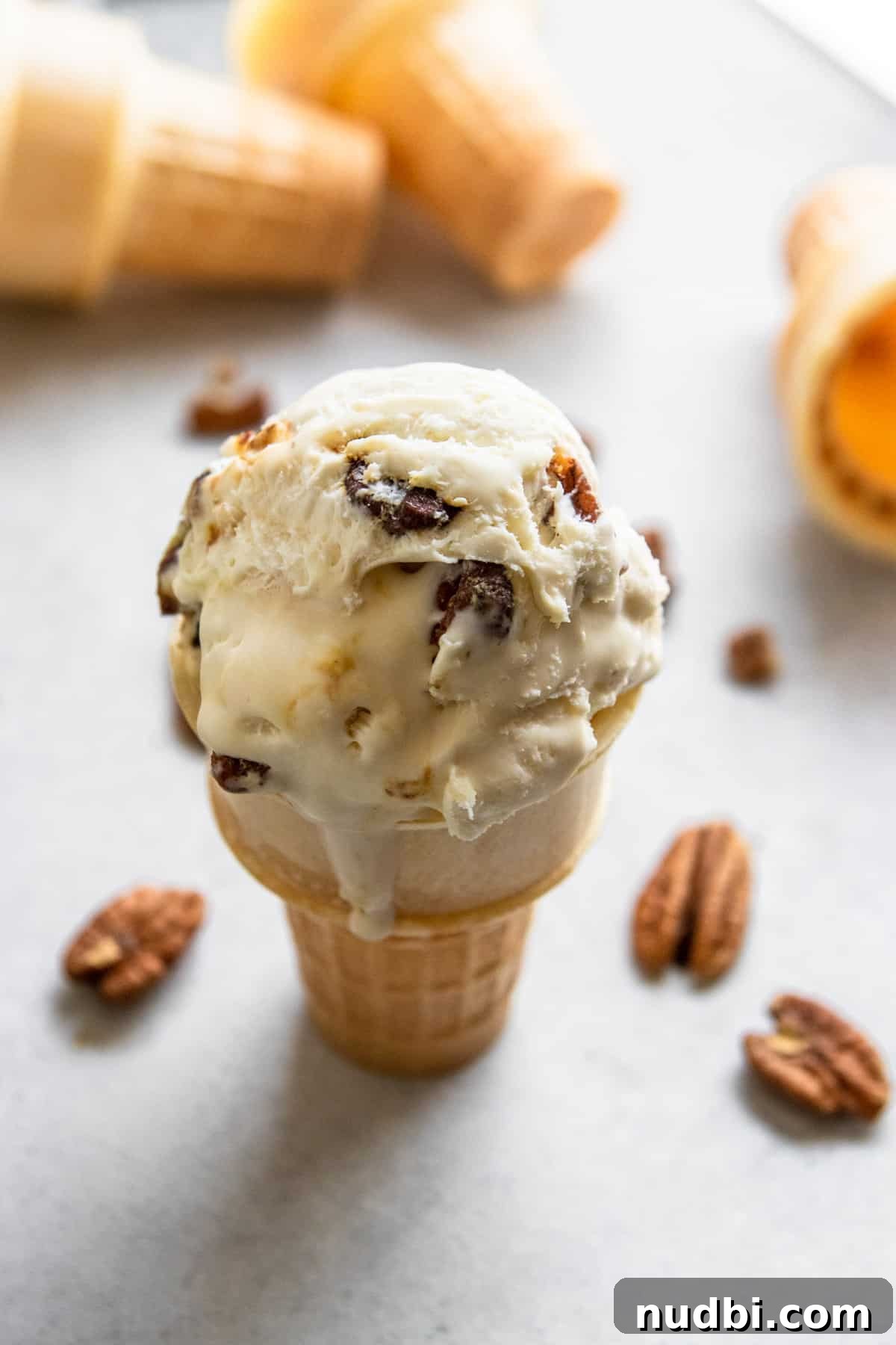 Homemade Butter Pecan Ice Cream Recipe You'll Love 2 butter pecan ice cream cone with pecans beside it.