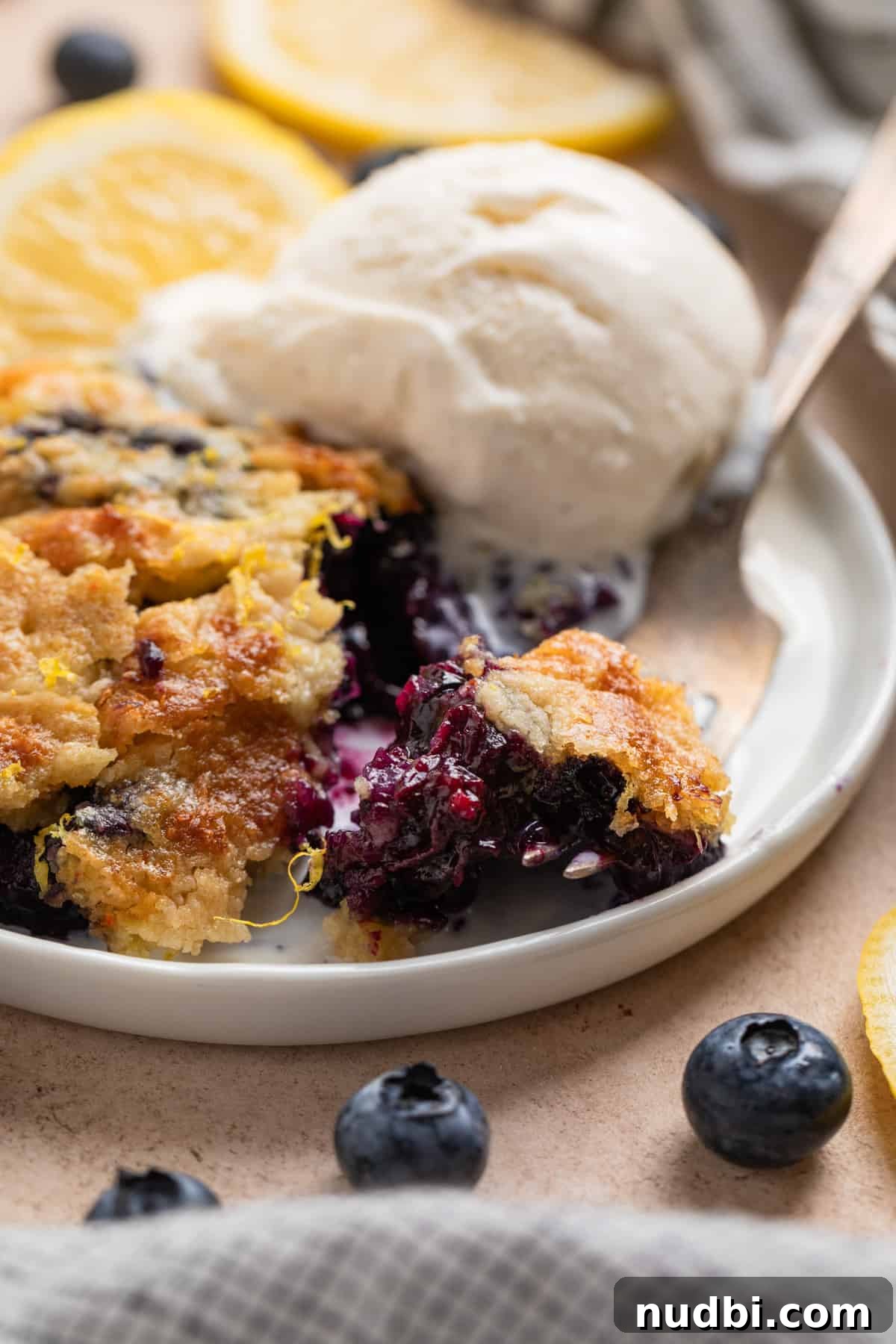 Lemon Blueberry Dump Cake Recipe for Quick Summer Desserts 10 White plate with slice of dump cake and fork with one forkful.