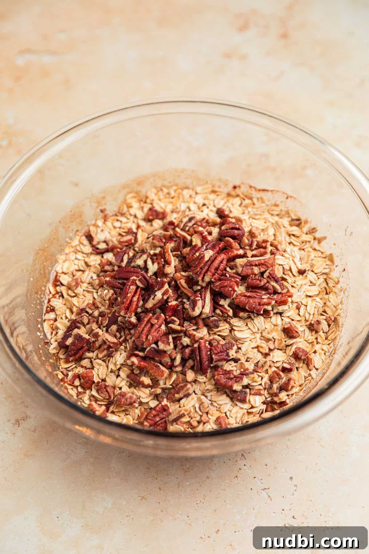 Banana Bread Granola Recipe — Crunchy Banana Oat Clusters 7 Rolled oats and pecans added to bowl with banana mixture.