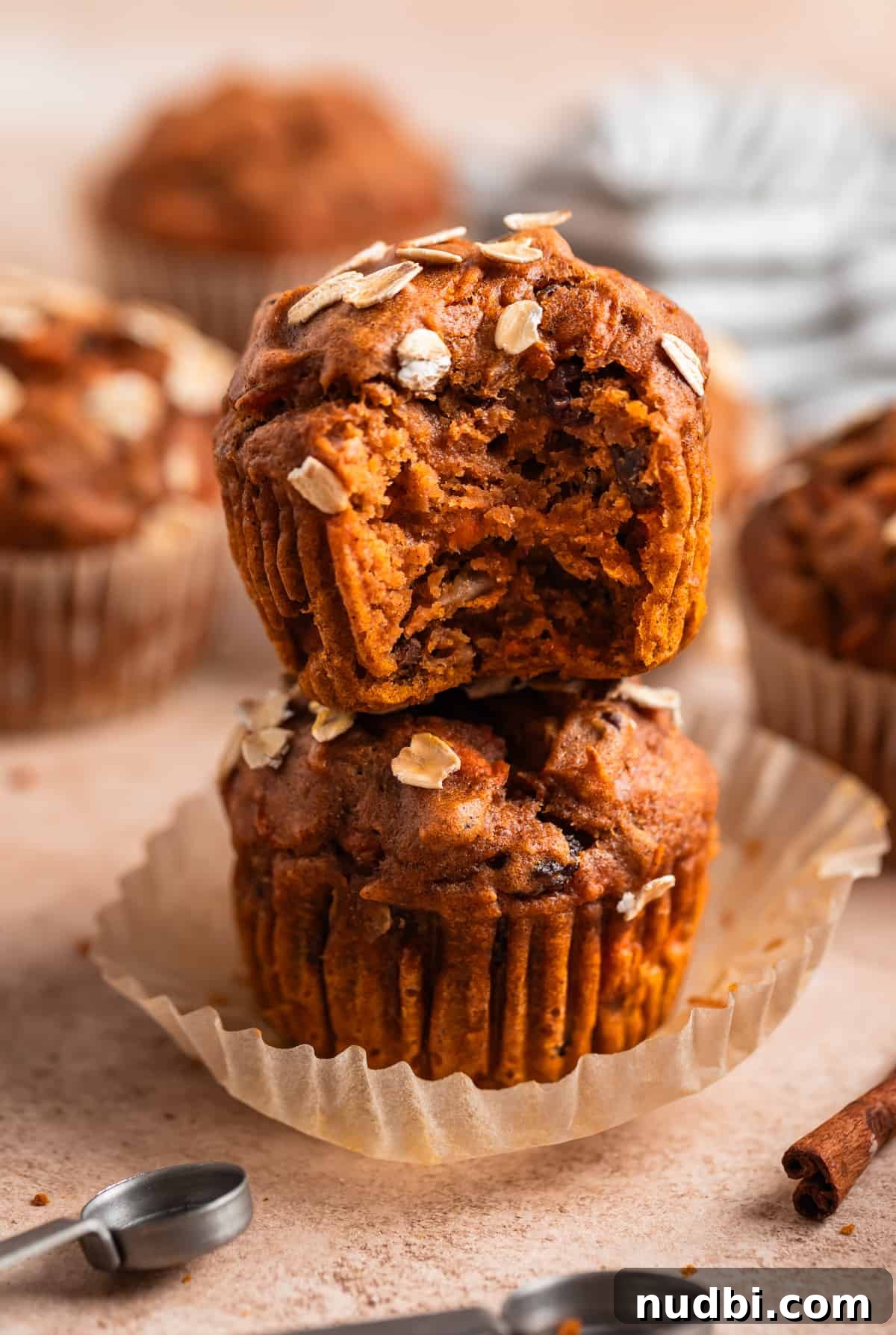 Moist Pumpkin and Carrot Muffins with Warm Spices 2 Pumpkin carrot muffin with bite taken out stacked on top of another muffin.