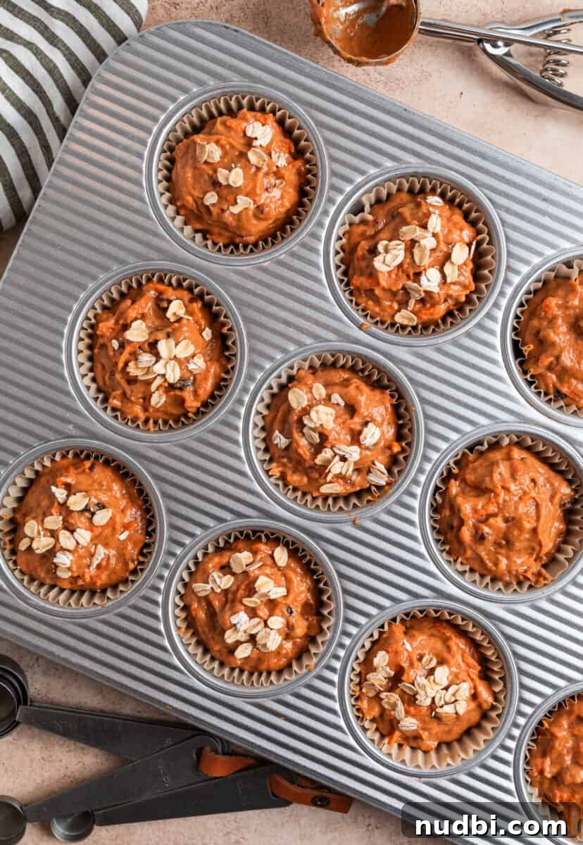 Moist Pumpkin and Carrot Muffins with Warm Spices 7 Pumpkin carrot muffin batter in muffin pan topped with rolled oats.