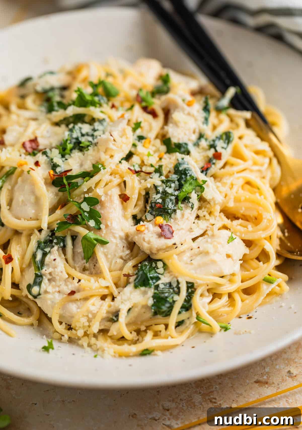 Creamy Parmesan Chicken in the Instant Pot: Tender 30-Minute Recipe 2 Instant pot creamy parmesan chicken tossed with pasta on plate and topped with chopped parsley and red pepper flakes.