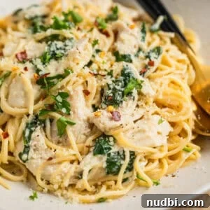 Creamy Parmesan Chicken in the Instant Pot: Tender 30-Minute Recipe 9 Instant pot creamy parmesan chicken tossed with pasta on plate with utensils.