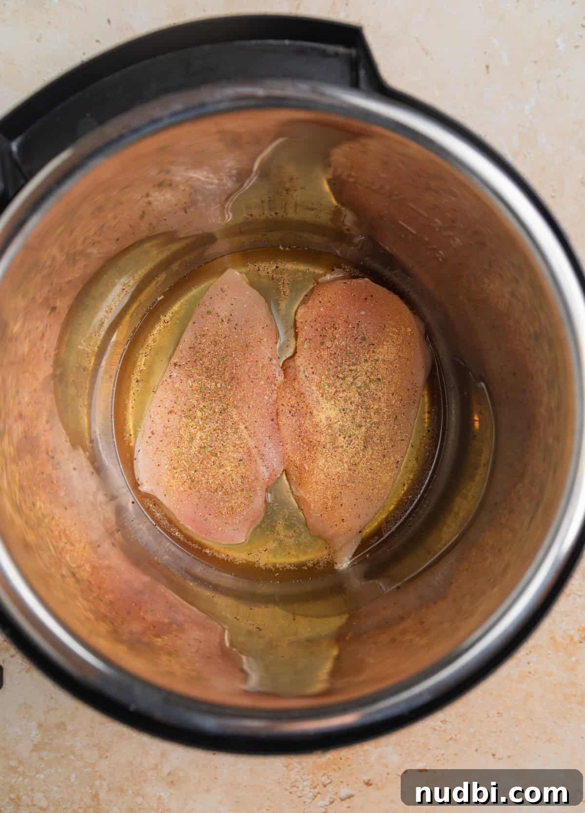 Creamy Parmesan Chicken in the Instant Pot: Tender 30-Minute Recipe 4 Chicken breast seasoned and placed in pressure cooker pot with broth.