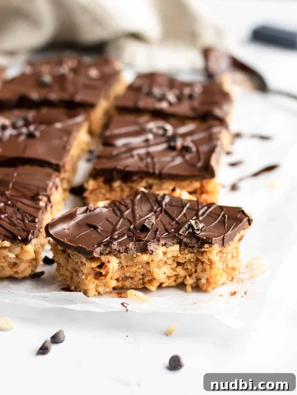 Chocolate Peanut Butter Rice Krispie Treats Recipe 3 Sliced rice crispy treats with peanut butter and chocolate layer with bite taken out of front piece.
