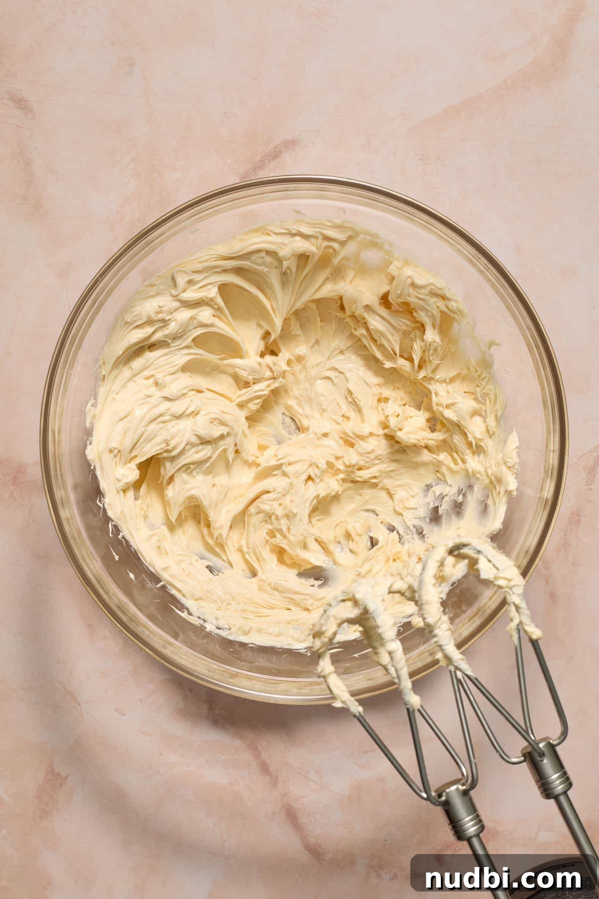 Perfect Cupcake Recipes Using Cake Mix for Fluffy Results 11 Butter creamed in glass bowl with mixer propped by the bowl.
