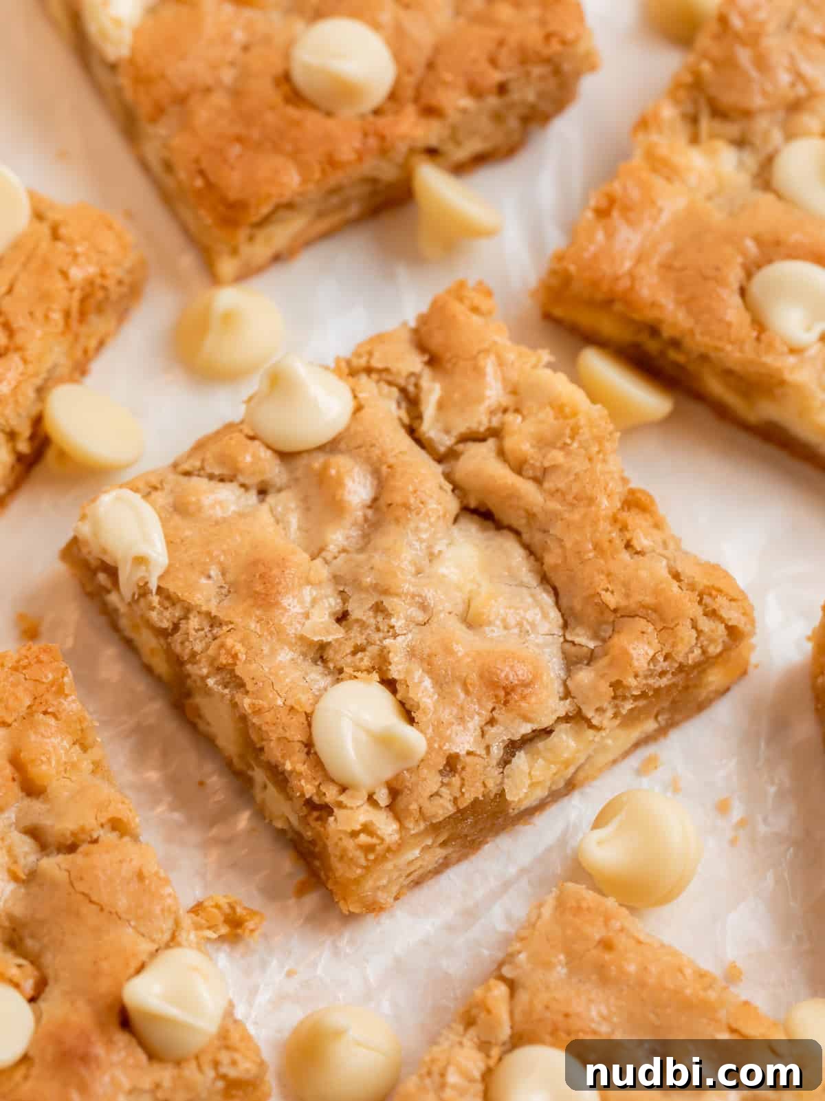 Chewy Gluten-Free Blondies Recipe That Melts in Your Mouth 3 Almond flour blondies lined on wax paper with white chocolate chips.