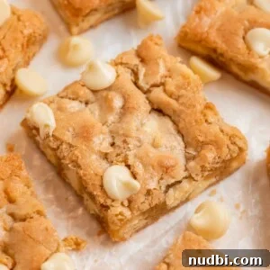 Chewy Gluten-Free Blondies Recipe That Melts in Your Mouth 9 Almond flour blondies on parchment with white chocolate chips.