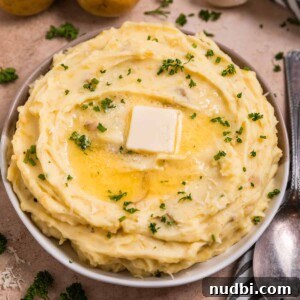 Garlic Parmesan Mashed Potatoes Made in the Instant Pot 8 Garlic parmesan mashed potatoes in serving dish with melted butter over top.
