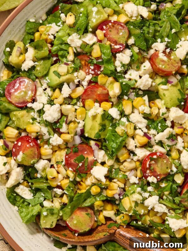 Spicy Cilantro Lime Black Bean Burgers 14 Salad with grilled corn, romaine, avocado, tomato in bowl.