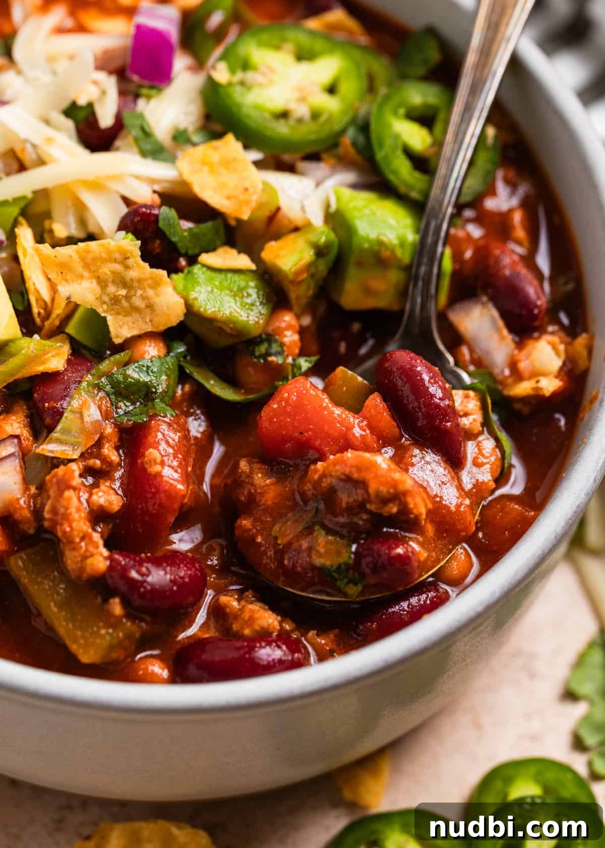 Hearty Turkey Chili Recipe for Cozy Weeknight Dinners 5 Bowl with chili and spoonful with ground turkey, beans and peppers.