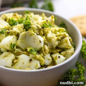 Avocado egg salad in bowl with chopped parsley.