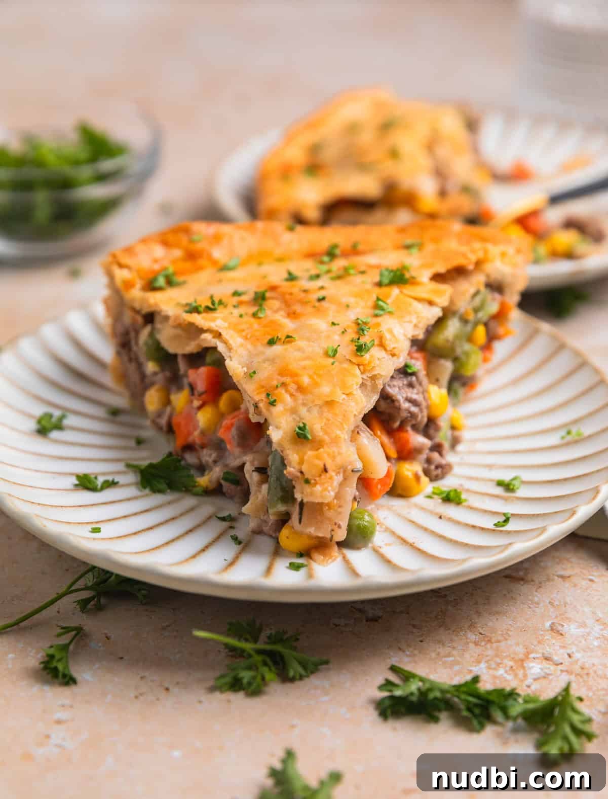 Savory Ground Beef Pot Pie Recipe with Flaky Crust 13 Slice of ground beef pie on dish with chopped parsley over top.
