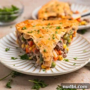 Savory Ground Beef Pot Pie Recipe with Flaky Crust 14 Slice of beef pot pie on plate topped with chopped parsley.
