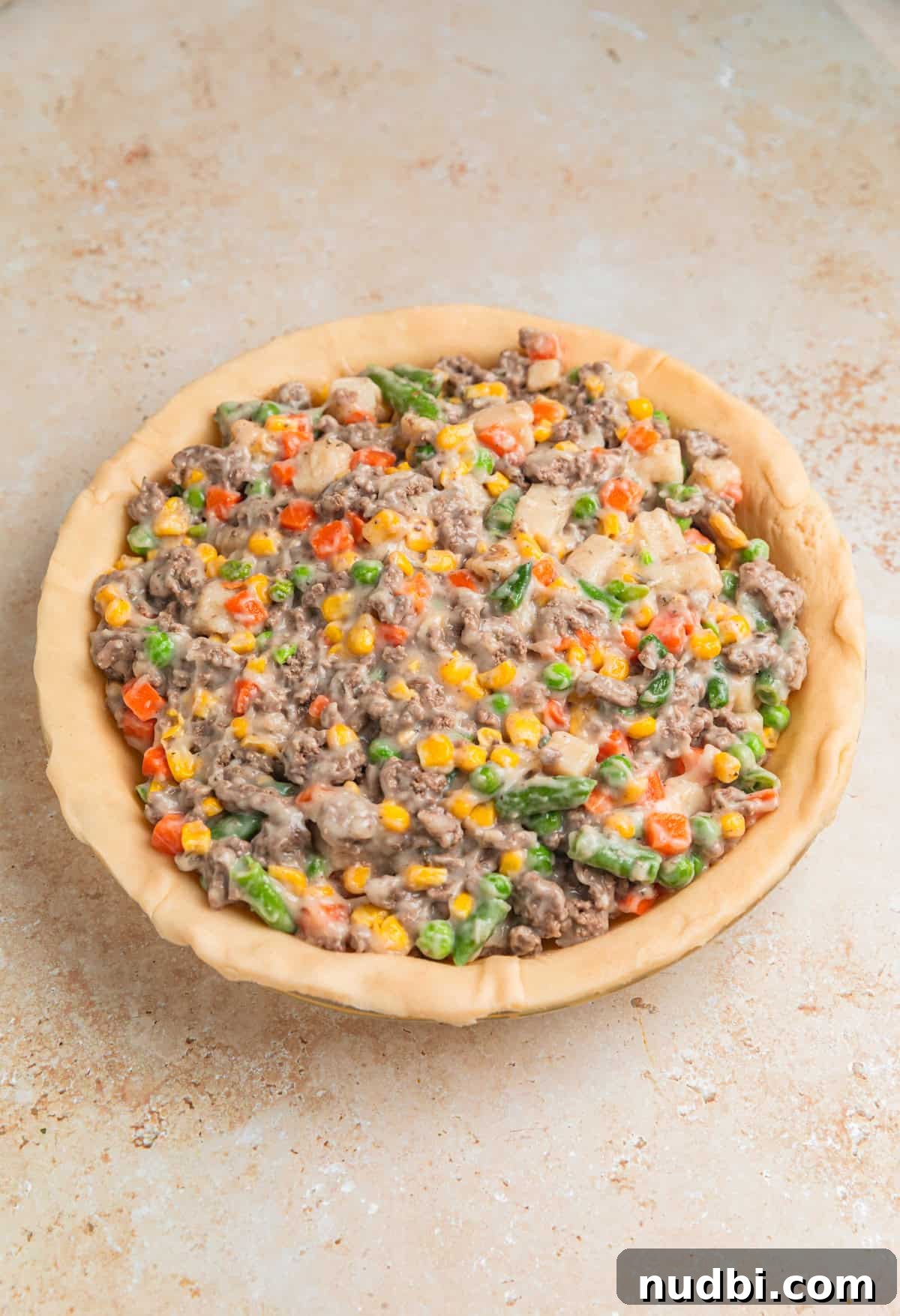 Savory Ground Beef Pot Pie Recipe with Flaky Crust 8 Pot pie with ground beef filling in pie dish over pie crust.