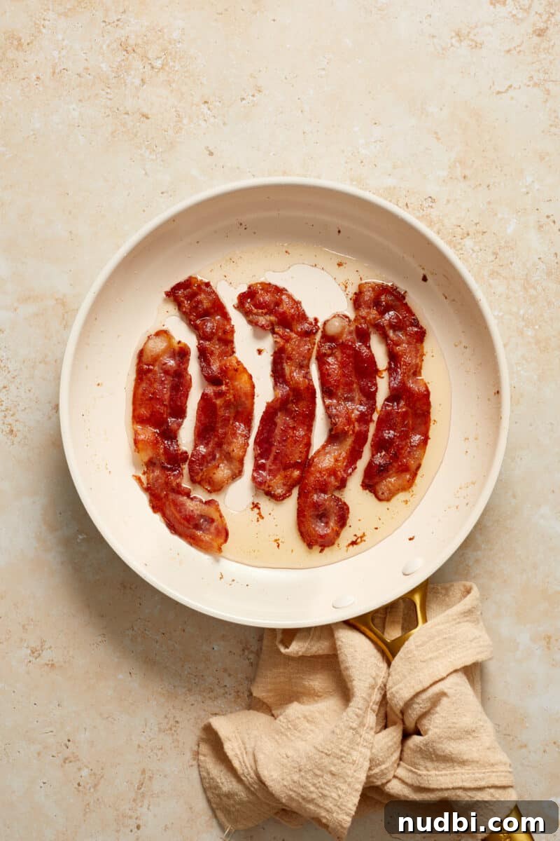 Cheesy Bacon Green Bean Casserole Recipe with Crispy Topping 4 Bacon cooked in skillet with linen around handle.