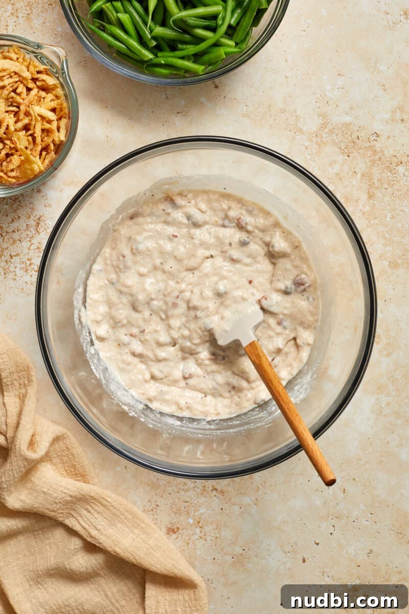 Cheesy Bacon Green Bean Casserole Recipe with Crispy Topping 5 Cream of mushroom soup mixture in mixing bowl with spatula.
