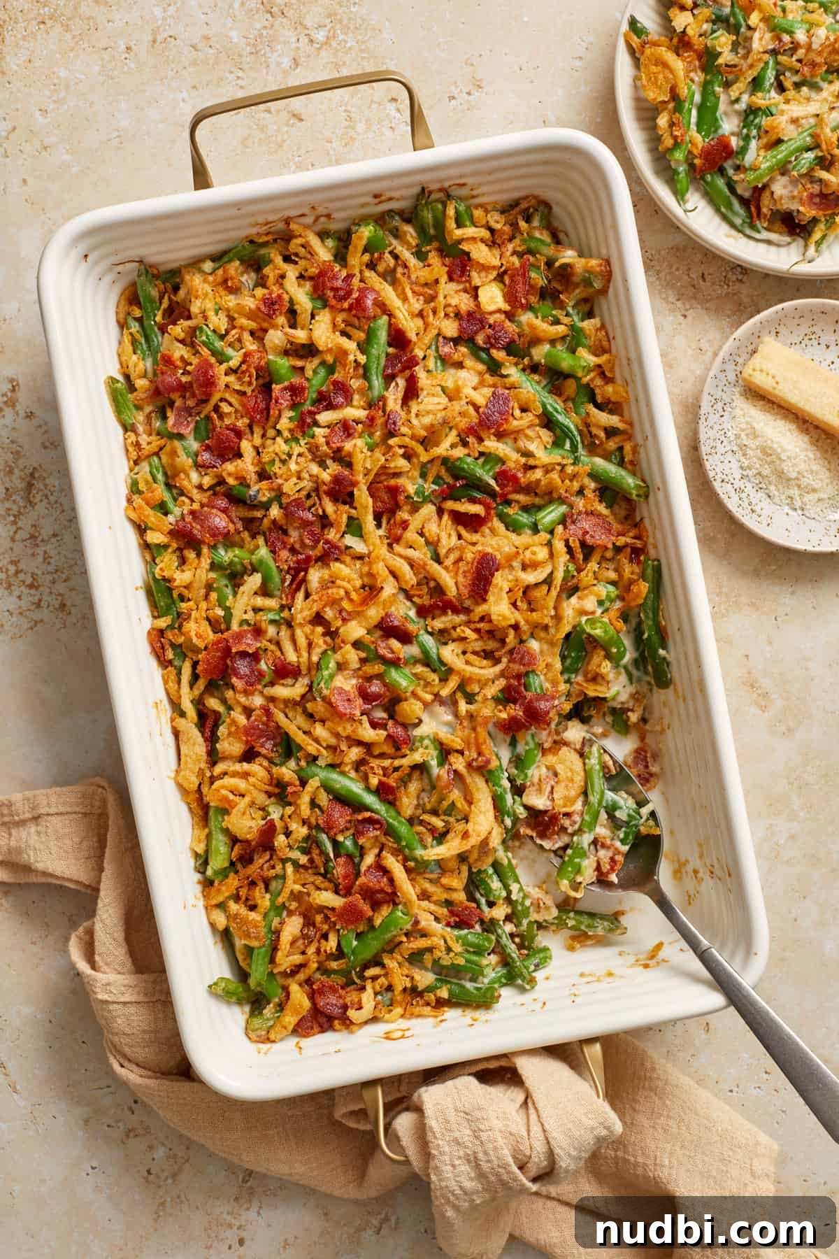 Cheesy Bacon Green Bean Casserole Recipe with Crispy Topping 9 Dish with green bean casserole with bacon with serving spoon.