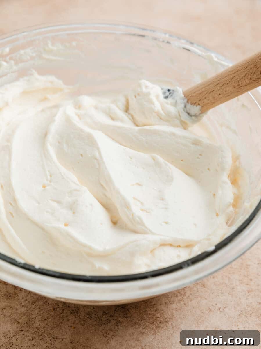 No-Bake Caramel Apple Cheesecake Recipe for Fall Gatherings 13 No bake cheesecake mixture in glass bowl with whipped cream folded into cheesecake mixture.