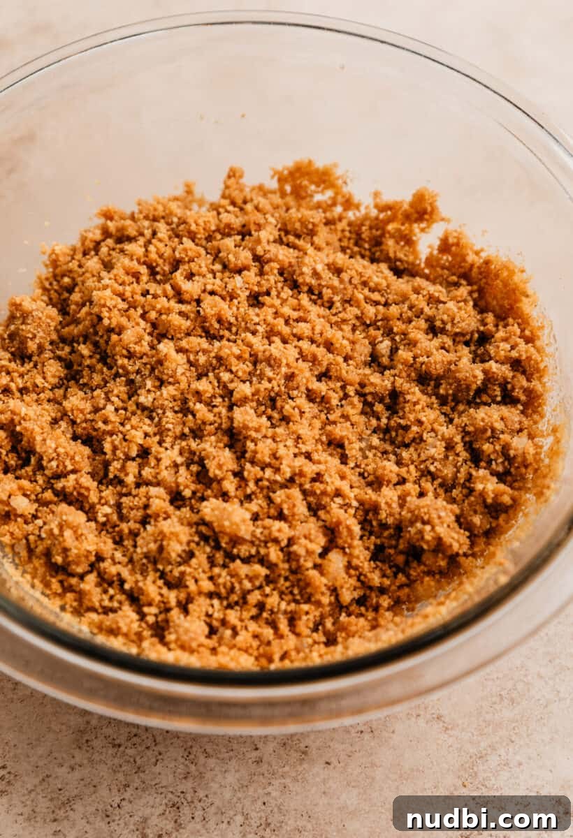 No-Bake Caramel Apple Cheesecake Recipe for Fall Gatherings 6 Graham cracker crust mixture in glass mixing bowl.