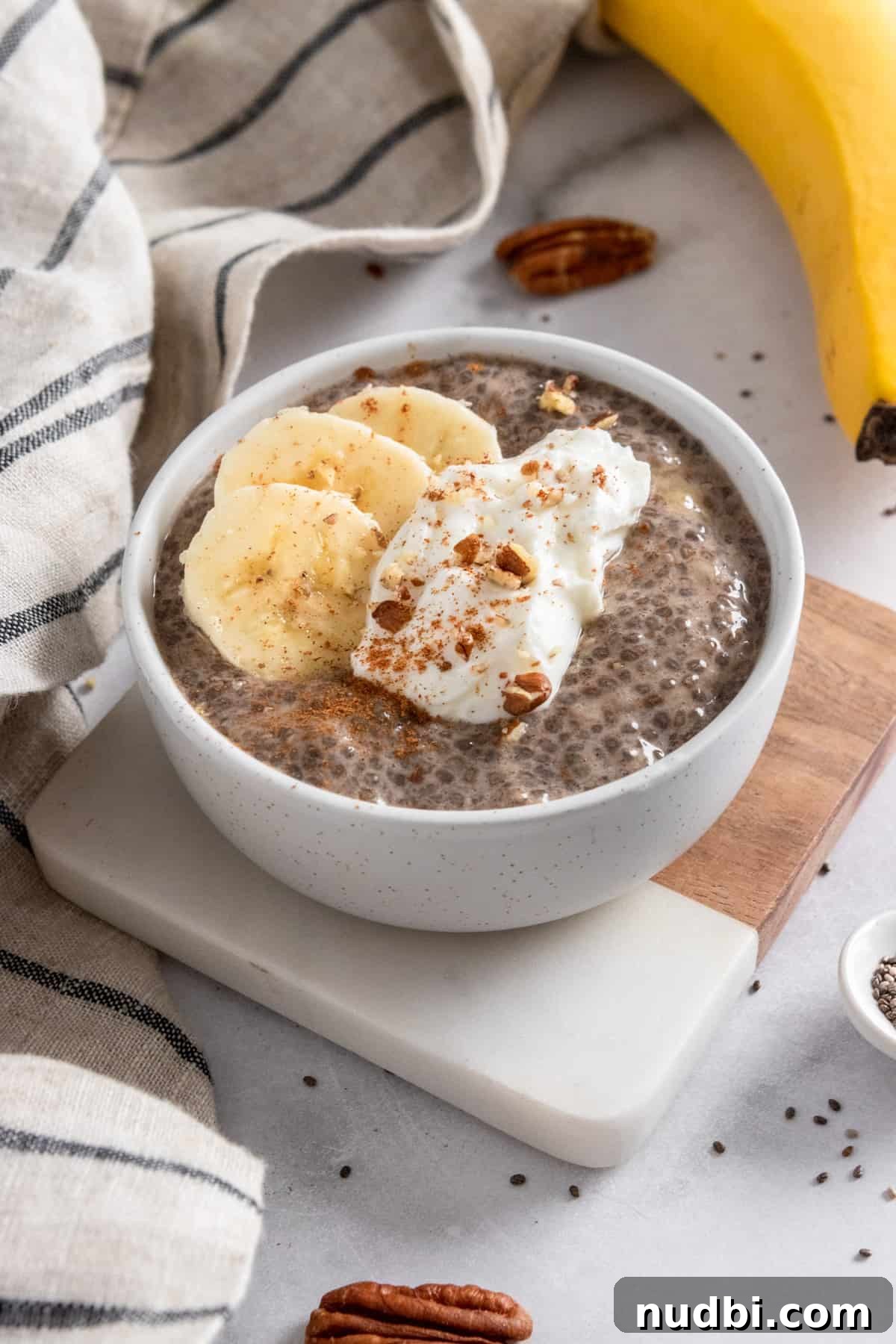 Creamy Banana Chia Seed Pudding Recipe for Breakfast & Snacks 2 Banana chia seed pudding in bowl with dollop of yogurt, banana slices and cinnamon on top.