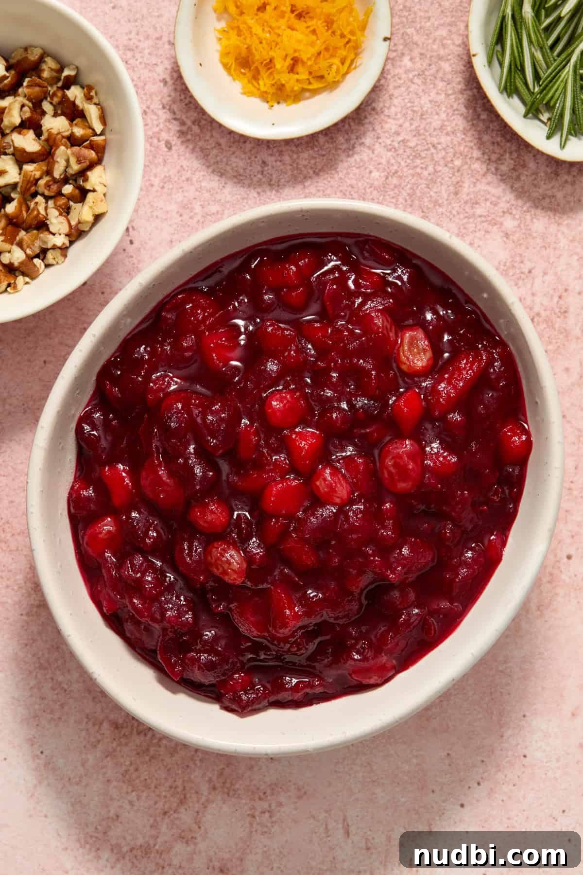 Cranberry Apple Chutney Recipe for Holidays and Leftovers 6 Bowl of cranberry chutney with bowls of rosemary, orange zest and pecans beside.