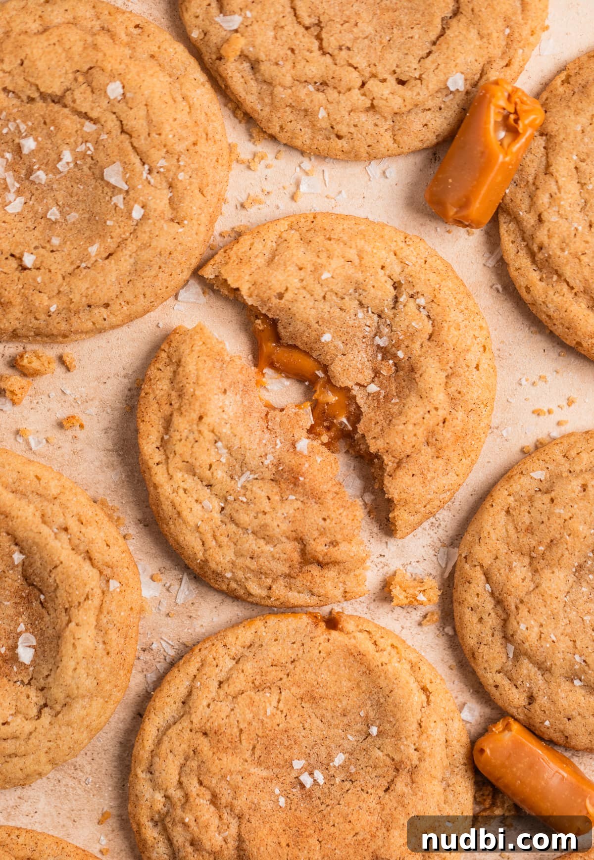 Chewy Snickerdoodle Cookies Filled with Caramel 15 Caramel stuffed snickerdoodle cookies arranged on surface with sea salt sprinkled over top.