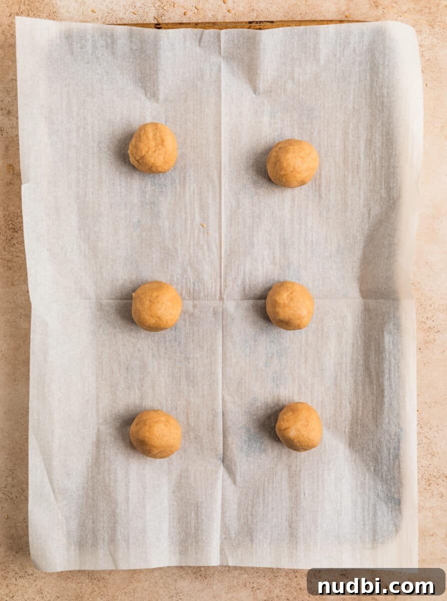 Chewy Snickerdoodle Cookies Filled with Caramel 8 Rolled Snickerdoodle cookie dough balls on parchment lined baking sheet.
