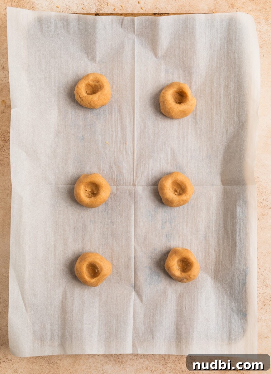 Chewy Snickerdoodle Cookies Filled with Caramel 9 Cooke dough balls with thumb imprint on cookie sheet.
