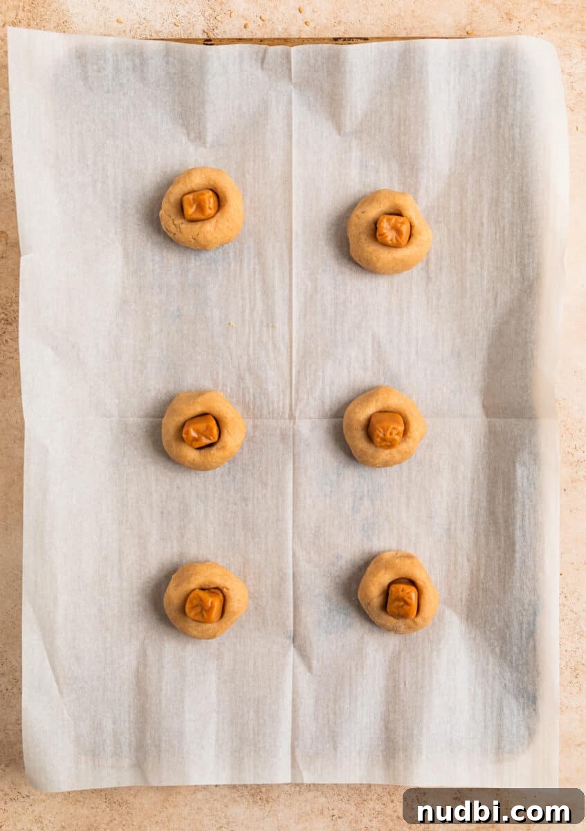Chewy Snickerdoodle Cookies Filled with Caramel 10 Caramel candies placed in thumbprint of cookie dough balls on baking sheet.