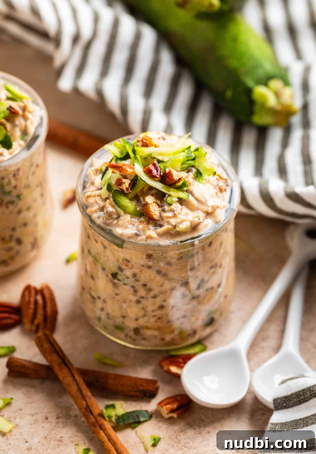 Overnight Zucchini Bread Oats — Moist, Spiced Breakfast Bowl 2 Zucchini overnight oats in jar with shredded zucchini and chopped pecans on top.