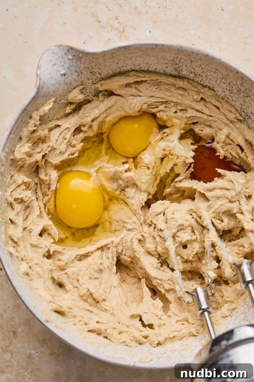 Oreo Chocolate Chip Cookies Recipe — Chewy Oreo-Stuffed Treats 8 Eggs and vanilla added to butter and sugar mixture in bowl.