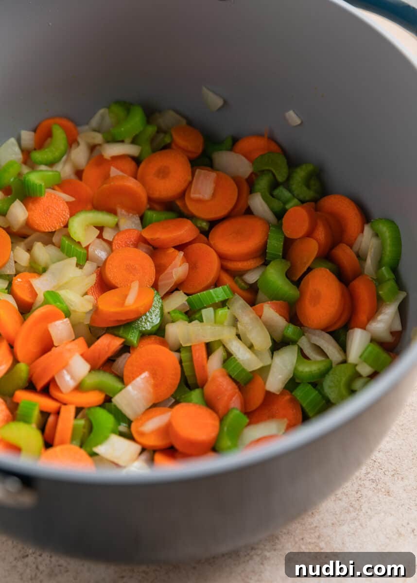 Rotisserie Chicken Noodle Soup Recipe for Quick Weeknight Meals 5 Carrots, celery and onion cooked in dutch oven pot.